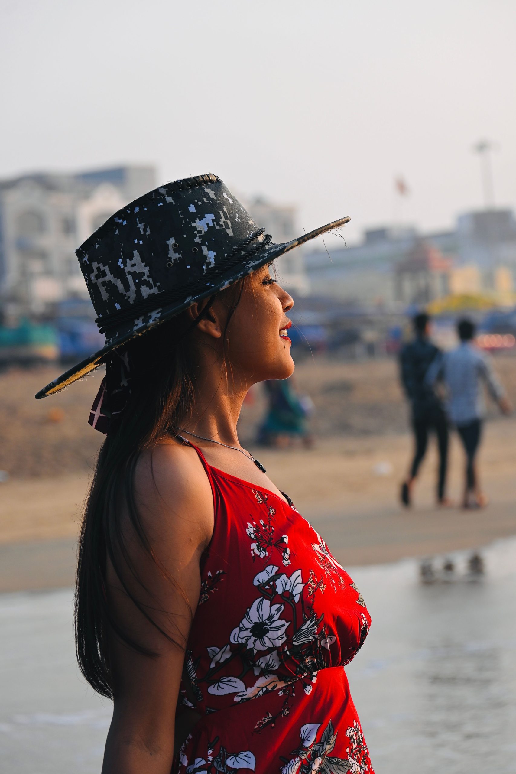 Portrait of a woman in a floral dress and hat standing by the beach in Puri, Odisha, India.